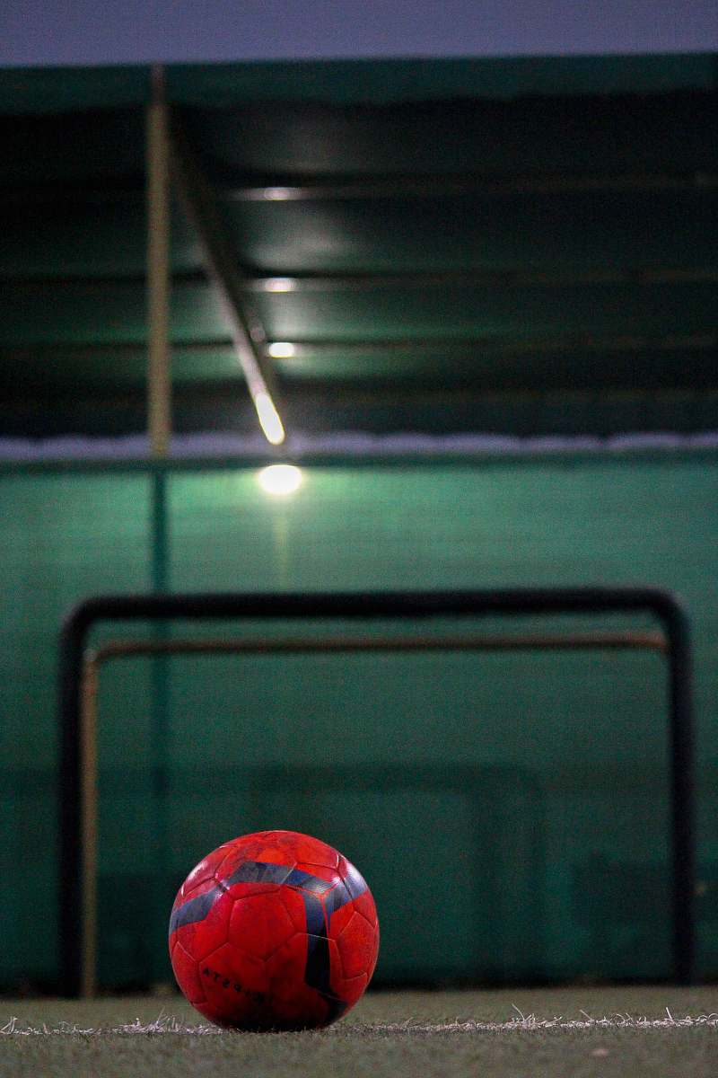 sphere selective focus photography of red soccer ball on field sports